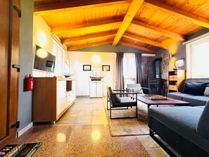 Ein gemütliches Wohnzimmer mit Kamin, einer Couch, einem Couchtisch und einem Essbereich mit einem Schiffsmodell.