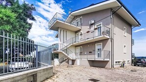 A multi-story residential building with balconies, a gated driveway, and a paved courtyard.