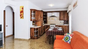A compact living space with a kitchen, dining area, and a sofa with a colorful pillow.