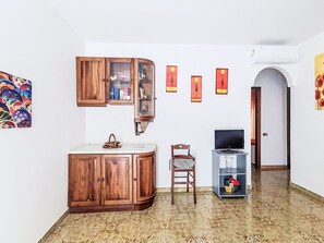 Une pièce avec un meuble en bois, une chaise, un meuble pour la télévision et un sol carrelé.