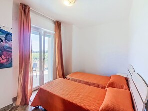 Une pièce avec un lit, une fenêtre avec des rideaux et un tableau au mur.