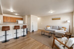 A modern kitchen with wooden cabinets, a refrigerator, and a dining area with a table and chairs. - Family 3BR/3.5BA W/ Cinema Near USAFA + Garden of the Gods (Colorado Springs)