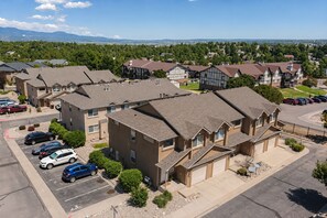 A residential area with multiple two-story houses, a parking lot with several cars, and a clear view of distant mountains. - Family 3BR/3.5BA W/ Cinema Near USAFA + Garden of the Gods (Colorado Springs)