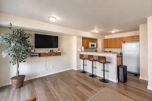 A modern kitchen with wooden cabinets, a built-in microwave, a refrigerator, and a bar area with stools. - Family 3BR/3.5BA W/ Cinema Near USAFA + Garden of the Gods (Colorado Springs)