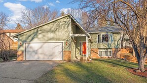 A two-story house with a garage, a front porch, and a small front yard. - Family-Friendly 4-Bed Retreat. Entire home in Eagan, Minnesota, United States (Eagan)
