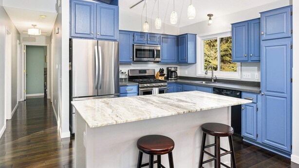 A modern kitchen with blue cabinets, stainless steel appliances, a marble island, and pendant lighting. - Family-Friendly 4-Bed Retreat. Entire home in Eagan, Minnesota, United States (Eagan)