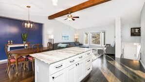 A spacious kitchen with a central island, wooden dining table, and chairs. There is a ceiling fan, pendant lights, and a view of the outside through a window. - Family-Friendly 4-Bed Retreat. Entire home in Eagan, Minnesota, United States (Eagan)