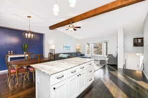 A spacious kitchen with a central island, wooden dining table, and chairs. There is a ceiling fan, pendant lights, and a view of the outside through a window. - Family-Friendly 4-Bed Retreat. Entire home in Eagan, Minnesota, United States (Eagan)