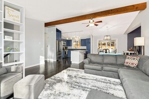 A modern living room with a gray sectional sofa, a white rug, and a kitchen in the background. - Family-Friendly 4-Bed Retreat. Entire home in Eagan, Minnesota, United States (Eagan)