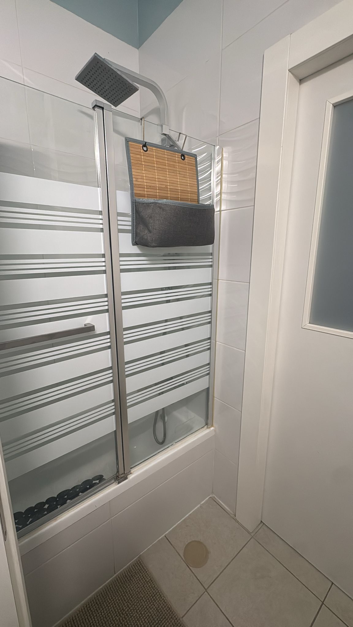 Een douche met een glazen deur, een handdoekhouder en een douchekop.