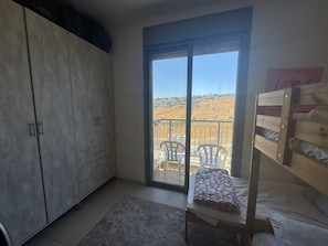 Een kamer met een stapelbed, een kledingkast, een schuifpui naar een balkon en een bordje op de deur.