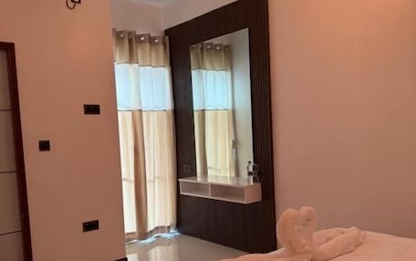 A hotel room with a large bed, a mirror, a wardrobe, and a bathroom visible through an open door.