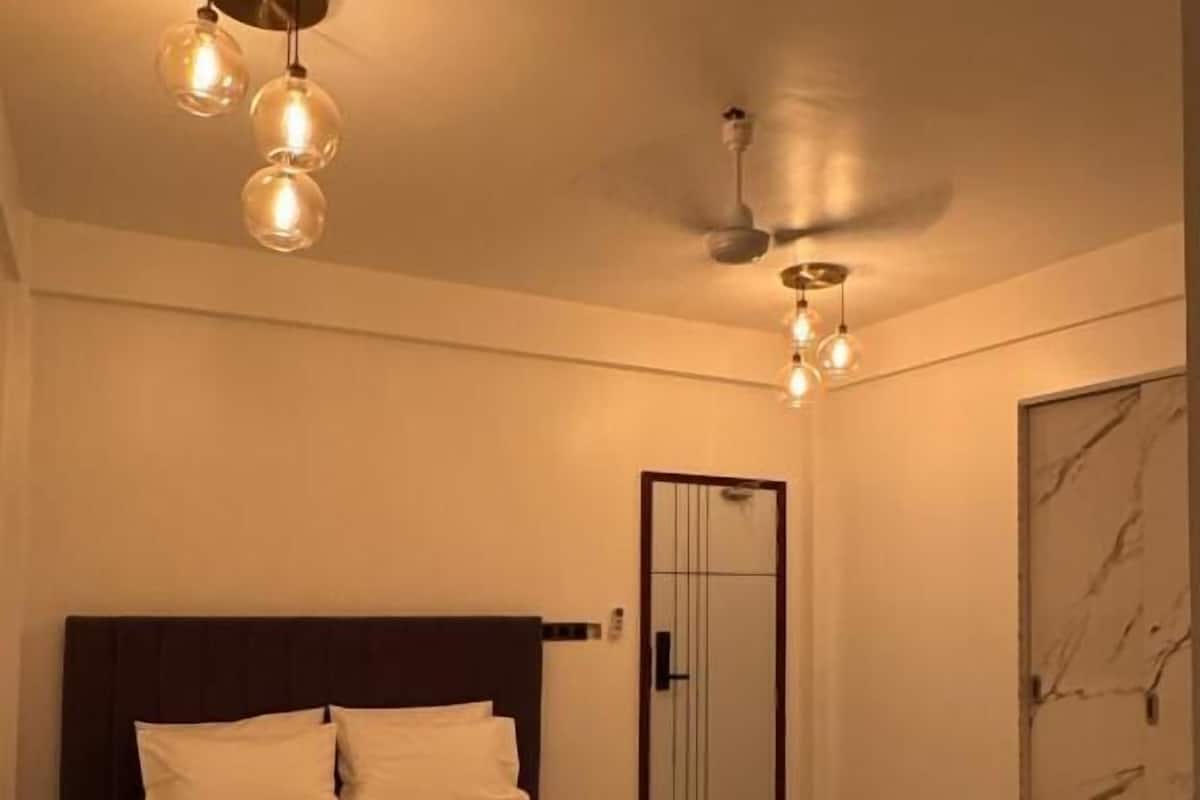 A bedroom with a bed, a door, and a marble wall.