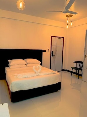 A bedroom with a bed, a ceiling fan, a door, and a chair. - Bonthi Grand (Gemanafushi)
