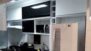 Una cocina compacta con microondas integrado, refrigerador de acero inoxidable y estufa a gas.