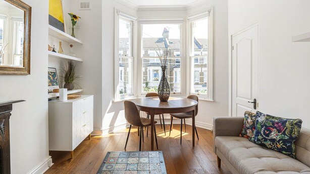 Une pièce comprenant une table à manger, des chaises, un canapé, une cheminée et une vue sur les bâtiments, visible à travers de grandes fenêtres.