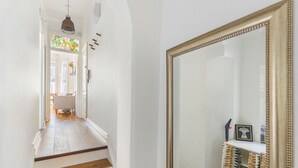 Un couloir avec un escalier, un grand miroir et une fenêtre à vitraux.