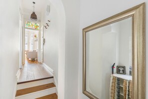 Ein Flur mit Treppe, einem großen Spiegel und einem Buntglasfenster.