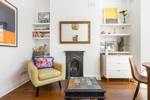 Ein Wohnzimmer mit Kamin, einer Couch, einem Couchtisch und einem Bücherregal.