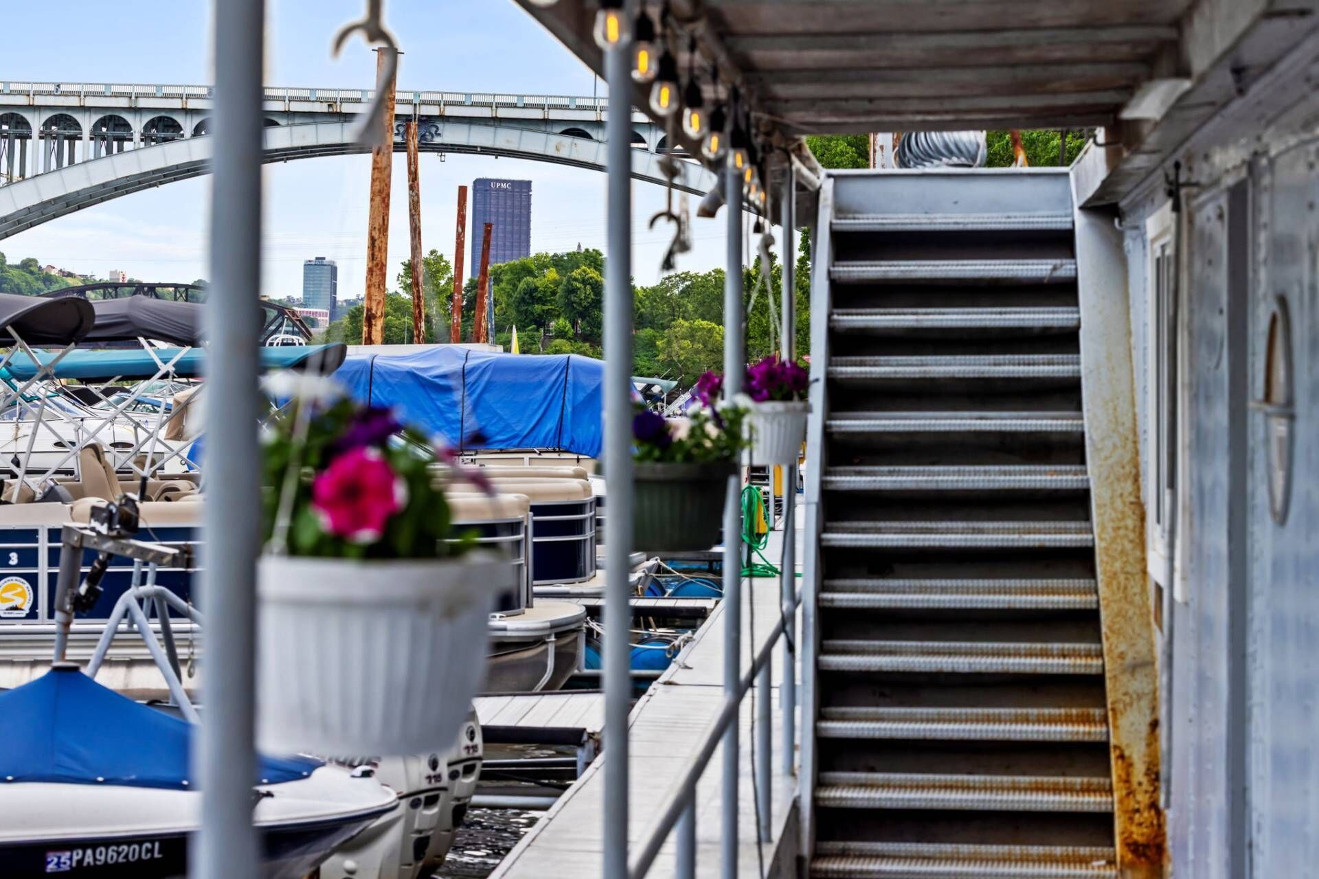 Un quai avec un escalier en métal, une zone abritée où sont amarrés des bateaux, et un pont en arrière-plan.