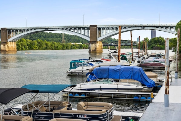 Un port de plaisance avec des bateaux amarrés, un pont en arrière-plan et une rivière.