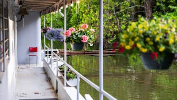 Un espace extérieur abrité, doté d’une balustrade blanche, de jardinières suspendues et d’une chaise rouge.