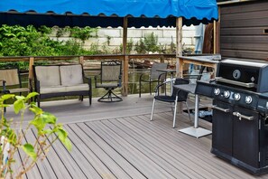 A wooden deck with a grill, outdoor furniture, and a covered area.