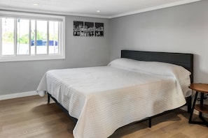 A bedroom with a bed, a window, and a wall-mounted picture.