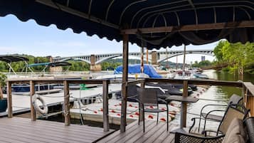 Une terrasse couverte offrant une vue sur une rivière, des bateaux et un pont.