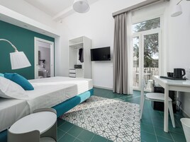 A modern hotel room with a bed, a desk, a TV, and a balcony with a view.