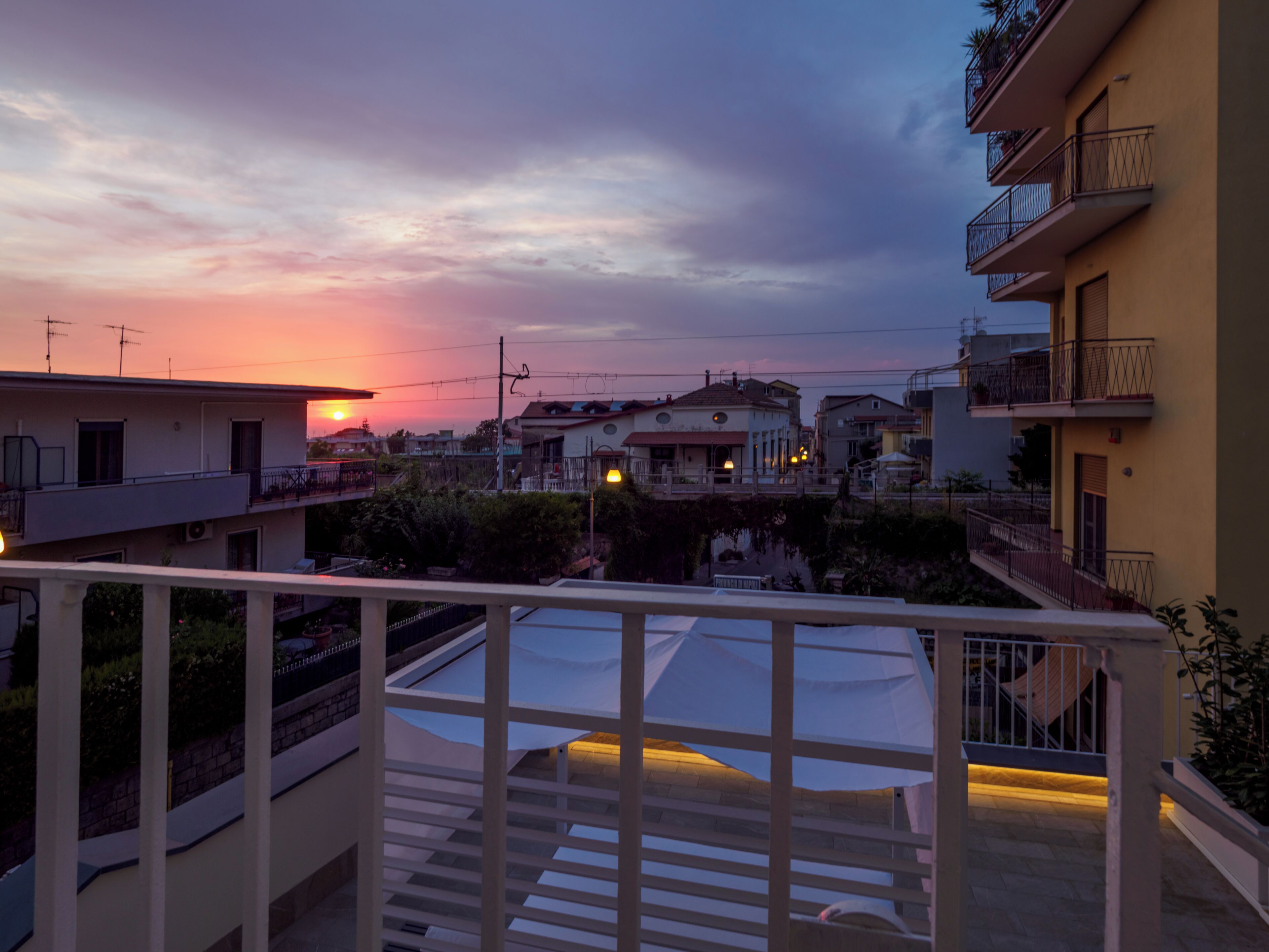 Ein Wohngebiet mit Gebäuden, einem Balkon und einem Sonnenuntergang.