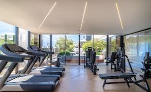 Ein Fitnessstudio mit Laufbändern, Kraftgeräten und einer Bank.