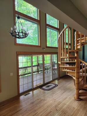 A spacious room with a wooden staircase, large windows, and a chandelier. - Casa Lago Retreat  (Topton)