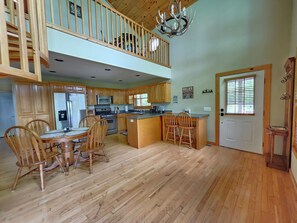 A spacious kitchen with wooden cabinets, a dining area with chairs, a central island, and a second-story balcony. - Casa Lago Retreat  (Topton)