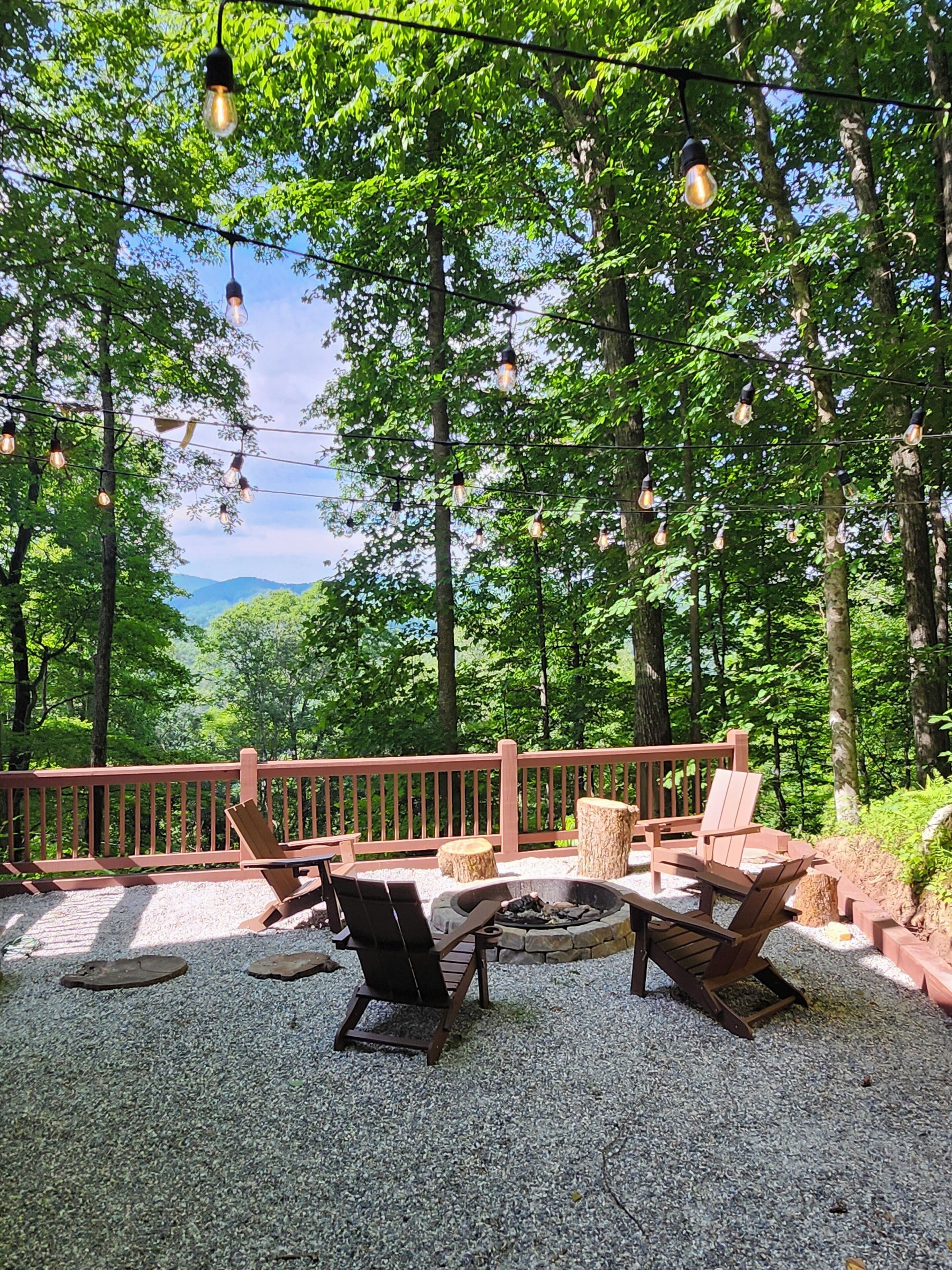 An outdoor seating area with a fire pit, wooden chairs, and a red railing.