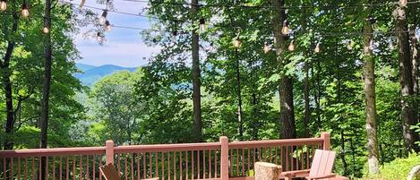 An outdoor seating area with a fire pit, wooden chairs, and a red railing.