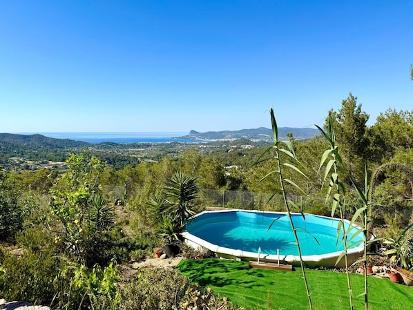 Une piscine entourée d’une végétation luxuriante, avec vue sur un paysage côtier.