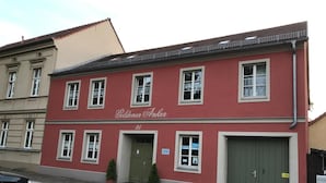 En rød bygning med skiltet 'Goldener Anker' og en grøn dør.