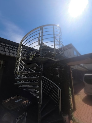 A spiral staircase with metal railings, a clear sky, and a vehicle parked outside. - Cozy and bright apartment in Lahde—in a quiet location, with a fully equipped kitchen (Petershagen)