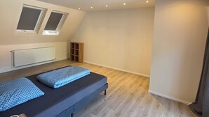 A modern bedroom with a loft bed, skylights, a radiator, and a wooden floor. - Cozy and bright apartment in Lahde—in a quiet location, with a fully equipped kitchen (Petershagen)