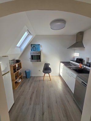 A modern kitchen with a skylight, built-in oven, and stainless steel appliances. - Cozy and bright apartment in Lahde—in a quiet location, with a fully equipped kitchen (Petershagen)