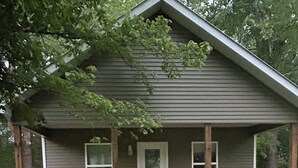 Una casa a un piano con un portico, una porta e due finestre.