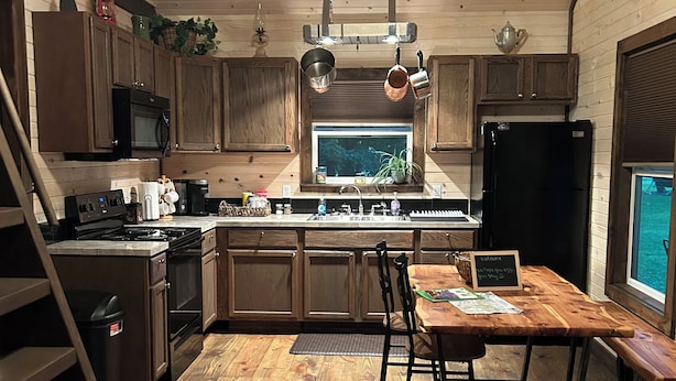 Una cucina con mobili in legno, un piano cottura e un'area pranzo con tavolo e sedie.