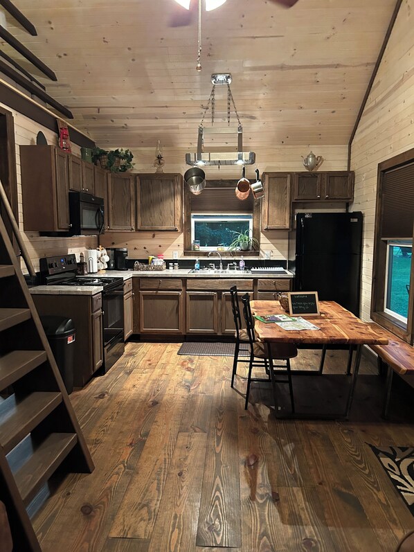 A kitchen with wooden cabinets, a stove, and a dining area with a table and chairs.
