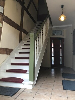 A staircase with white steps and red risers, leading to a door with frosted glass panels.