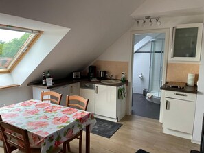 Eine kleine Küche mit Essbereich, einem Fenster und einer Dusche.