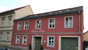 A red building with the sign 'Goldener Anker' and a green door. - Golden Anchor Cozy Holiday Apartment in the Center of Rheinsberg (Rheinsberg)