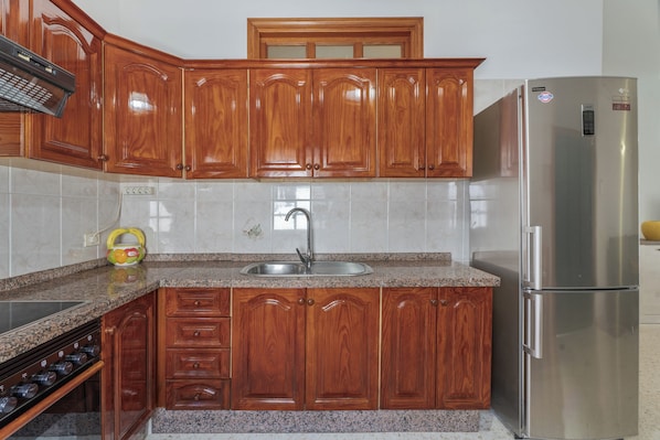 Eine Küche mit Holzschränken, einem Edelstahlkühlschrank und einer Granitarbeitsplatte.
