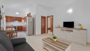 A modern living room with a sofa, a coffee table, and a TV on a wooden cabinet. - Charming Bungalow Rental in Abades, Spain - Perfect Family Retreat (Arico)