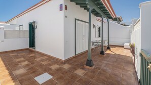 A building with a tiled roof, a covered patio area, and a door with a window. - Charming Bungalow Rental in Abades, Spain - Perfect Family Retreat (Arico)